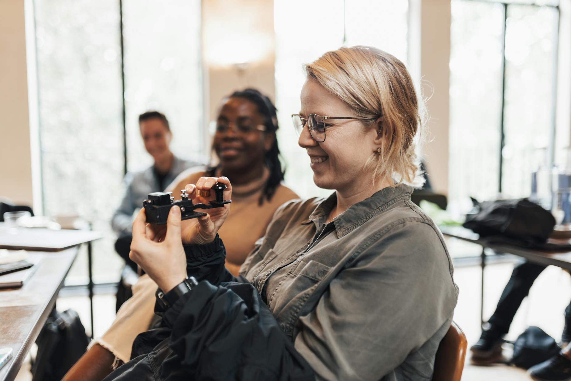 Uśmiechnięta kobieta trzymająca zestaw VR w jasnym pomieszczeniu