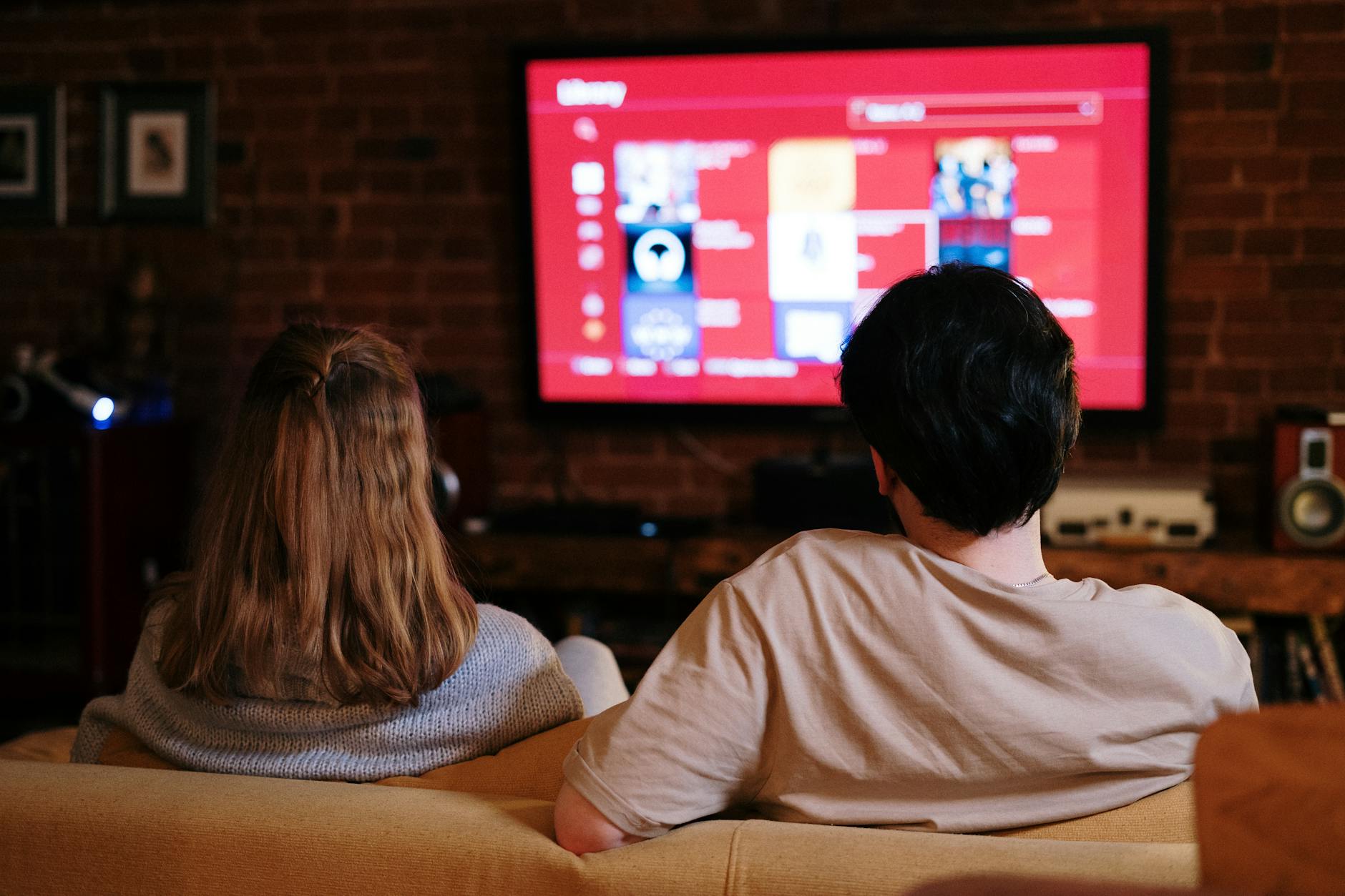 Para ogląda serial na dużym telewizorze w przytulnym salonie z cegłą