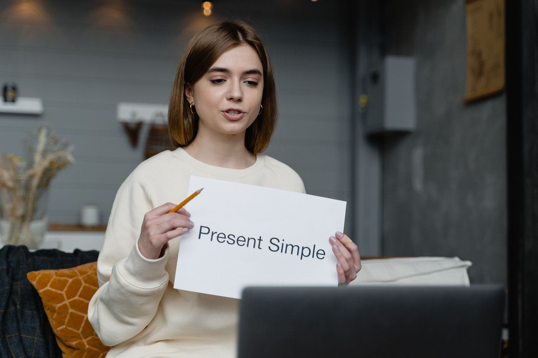 Kobieta uczy gramatyki angielskiej online, pokazuje Present Simple