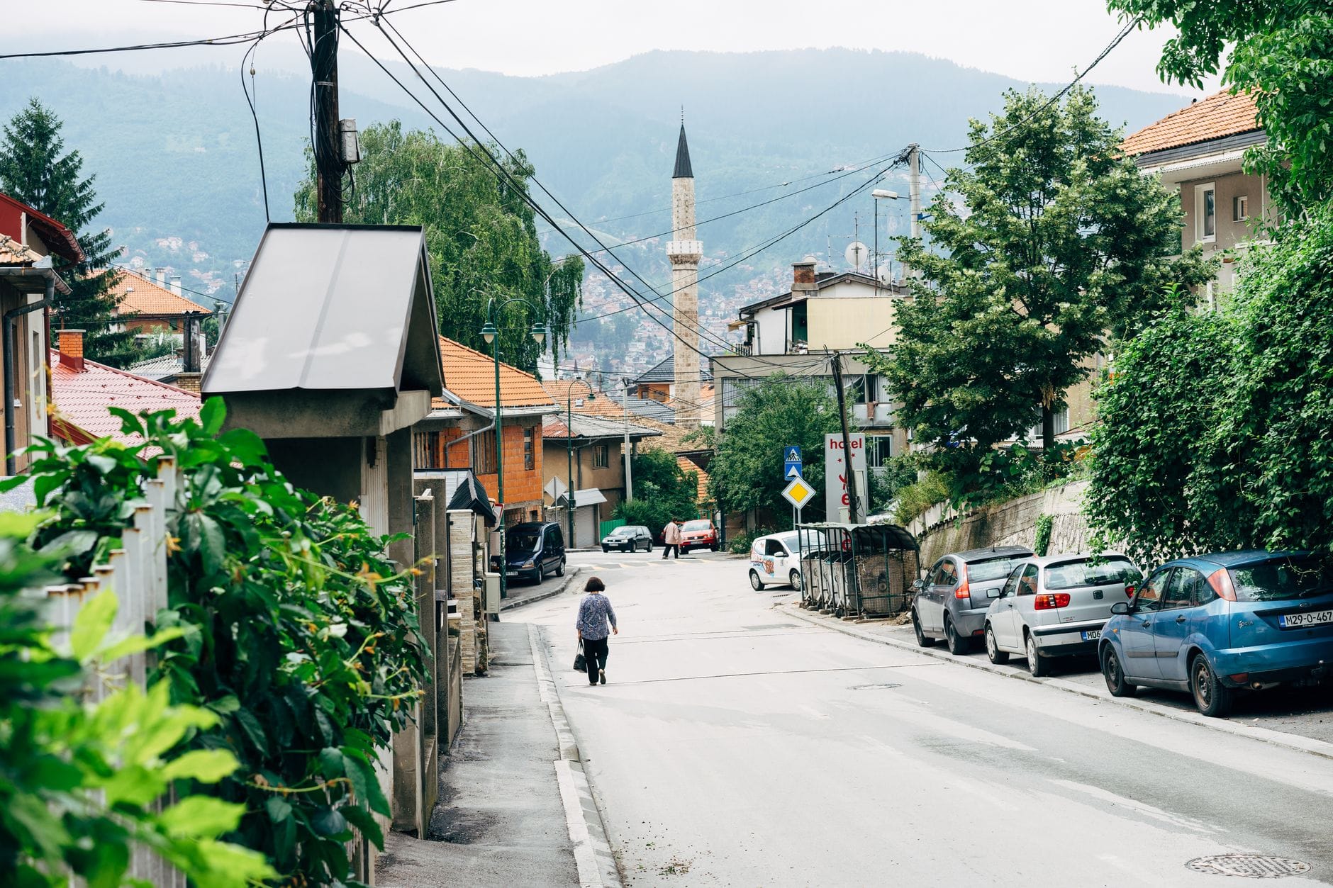 Ulica w Sarajewie z minaretem meczetu i zaparkowanymi samochodami