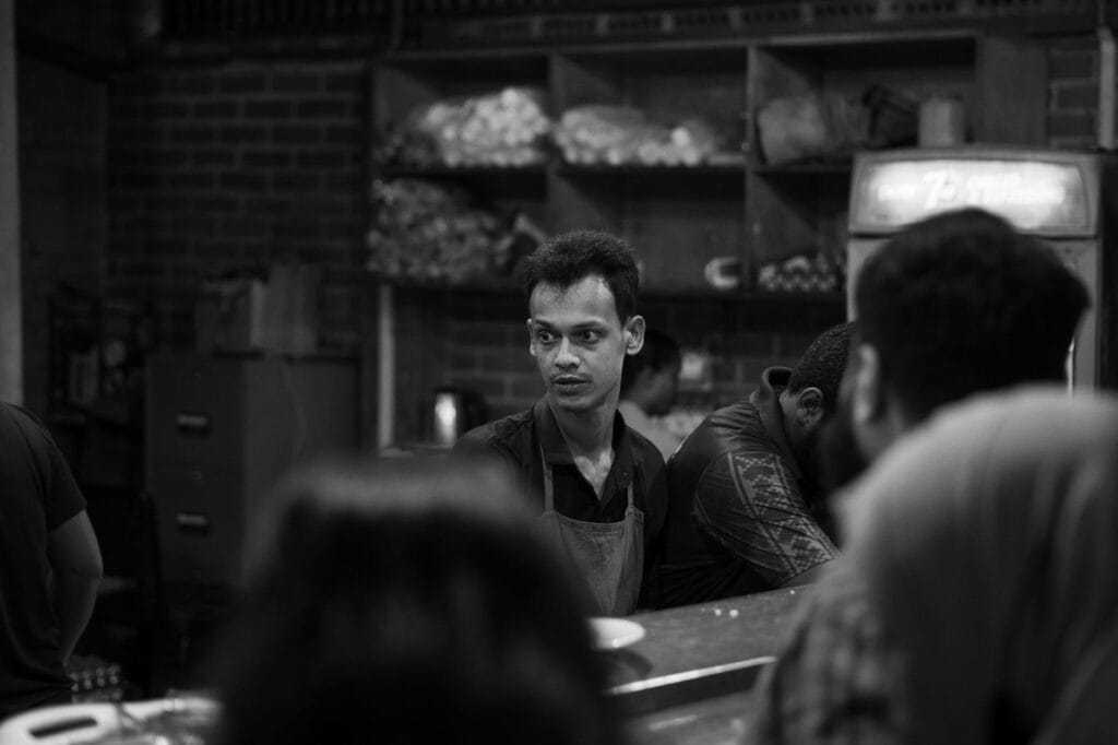 Barista w fartuchu pracuje w zatłoczonej kawiarni