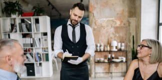 Kelner przyjmuje zamówienie od starszej pary w nowoczesnej restauracji